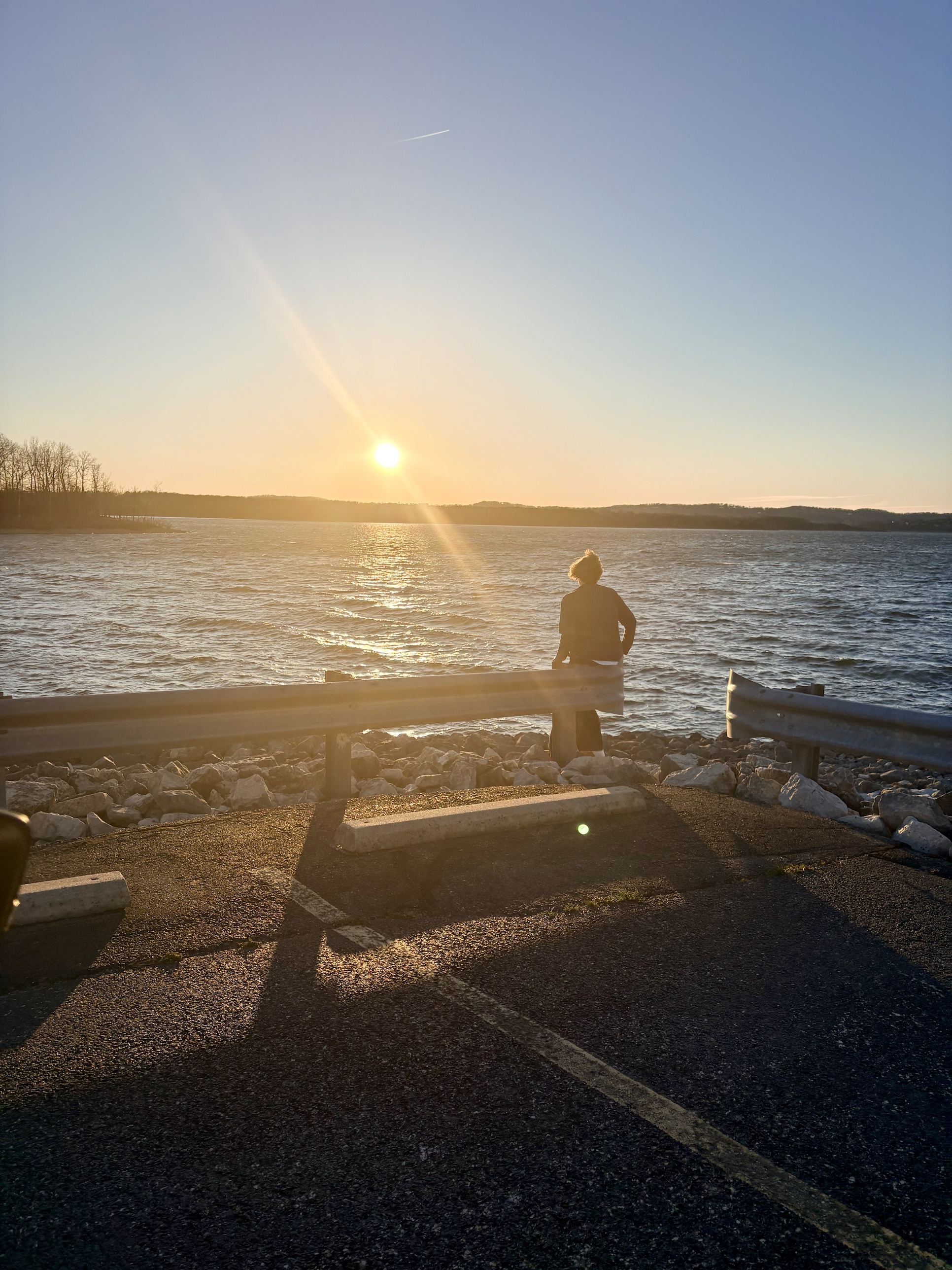 A woman watching the sunset over the water, a quiet moment of reflection